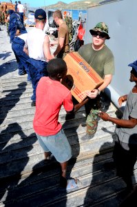 US Navy 080922-N-7955L-078 U.S. service members assigned to the amphibious assault ship USS Kearsarge (LHD 3) and Haitian civilians move boxes of cooking oil during a humanitarian assistance mission to aid Haitians affected by photo