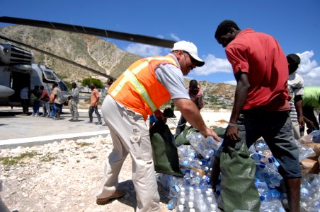 US Navy 080922-N-9620B-003 Haitian relief workers help U.S. military service members embarked aboard the amphibious assault ship USS Kearsarge (LHD 3) unload food and water to aid those affected by the recent hurricanes that ha