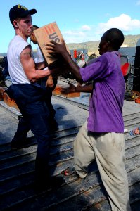 US Navy 080922-N-7955L-112 Aviation Ordnanceman Airmen Travis Pillow, assigned to the amphibious assault ship USS Kearsarge (LHD 3), gives a box of cooking oil to a Haitian citizen during a humanitarian assistance mission to ai