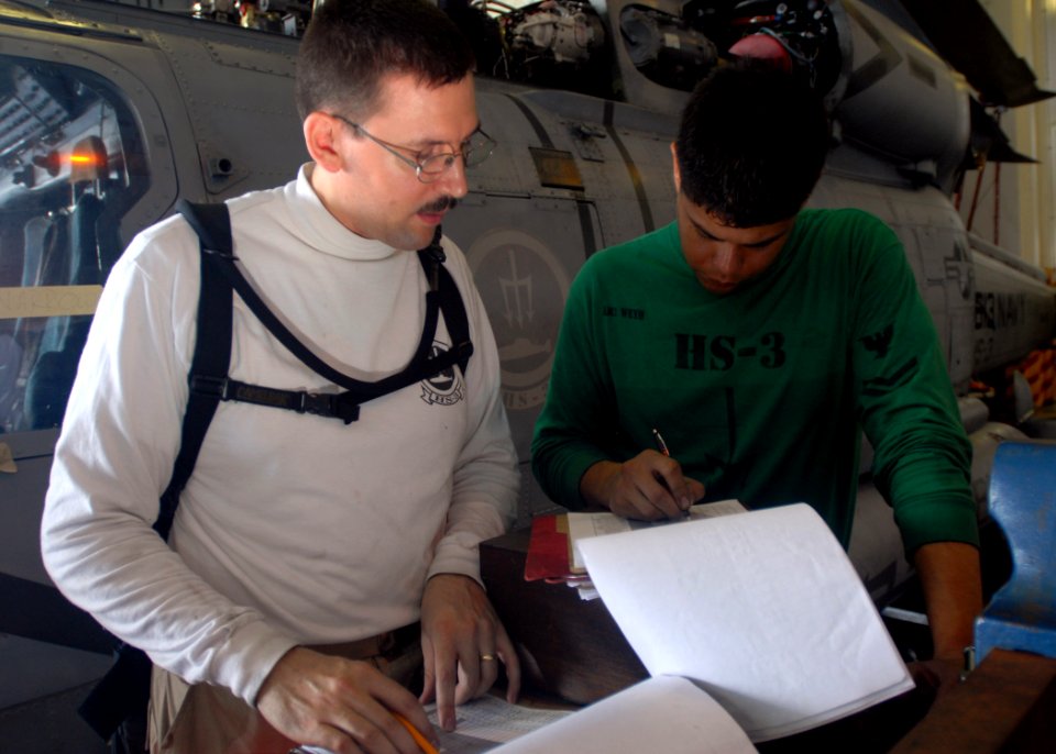 US Navy 080923-N-2456S-024 ATC Phillip Crosby and AM2 Todd Weyh review phase inspection packages for job completion signature blocks for the SH-60F Sea Hawk aboard USS Theodore Roosevelt (CVN 71)