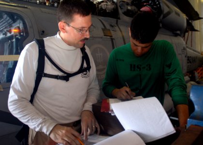 US Navy 080923-N-2456S-024 ATC Phillip Crosby and AM2 Todd Weyh review phase inspection packages for job completion signature blocks for the SH-60F Sea Hawk aboard USS Theodore Roosevelt (CVN 71)