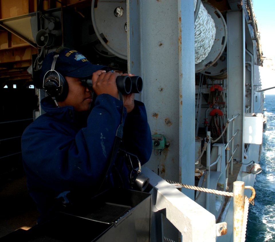 US Navy 080923-N-4021H-061 Boatswain's Mate Seaman Lenie Jordan peers through binoculars while standing the aft look-out watch