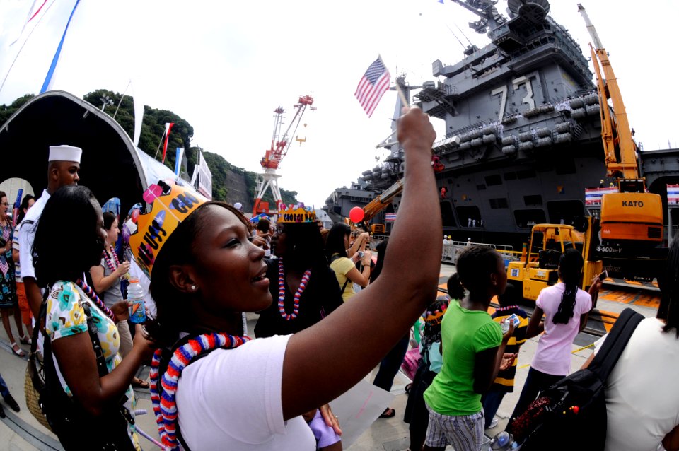 US Navy 080925-N-8546L-472 A woman waves an American flag to greet a family member assigned to USS George Washington (CVN 73)