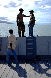 US Navy 080923-N-9620B-007 Boatswain's Mate Chief Sultan Hamzah, embarked aboard the amphibious assault ship USS Kearsarge (LHD 3), gives advice to a Haitian boy after unloading relief supplies from a utility landing craft photo