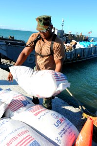 US Navy 080922-N-7955L-003 Hospital Corpsman 3rd Class Mikel Frazier, an individual augmentee assigned to the amphibious assault ship USS Kearsarge (LHD 3), stacks bags of flour