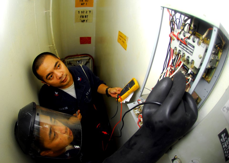 US Navy 080925-N-5148B-013 Electrician's Mate 2nd Class Roel Villansin and Electrician's Mate 2nd Class Rem Cepeda trouble shoot ventilation in an ammo storage cargo hold