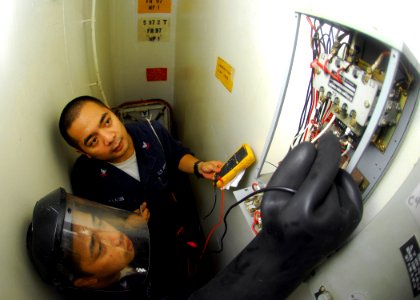 US Navy 080925-N-5148B-013 Electrician's Mate 2nd Class Roel Villansin and Electrician's Mate 2nd Class Rem Cepeda trouble shoot ventilation in an ammo storage cargo hold