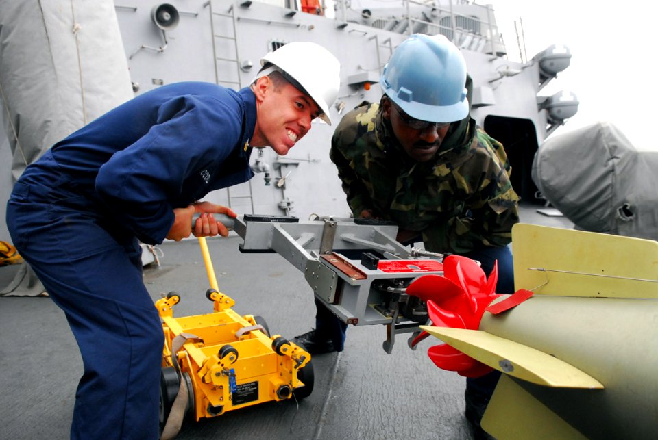 US Navy 080929-N-2013O-001 Gunner's Mate 1st Class Justin McConnell and Gunner's Mate 2nd Class Lamar Varnedoe upload a torpedo