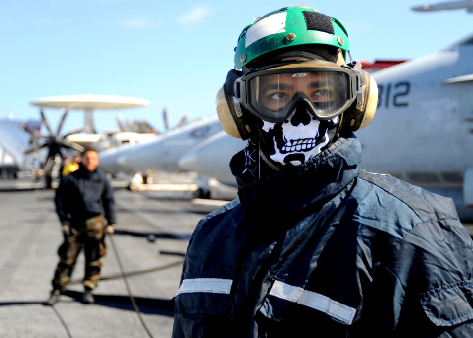 US Navy 081001-N-7571S-005 Aviation Boatswain's Mate (Equipment) Airman Yuri Fernandez looks towards the bow of the aircraft carrier USS Theodore Roosevelt (CVN 71) to ensure there are no personnel near the catapults before fli