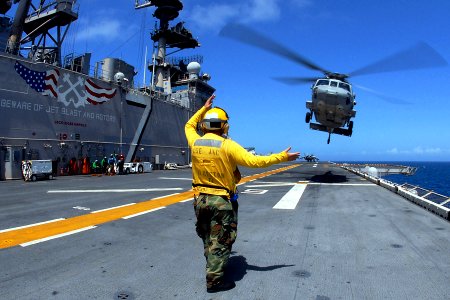 US Navy 081001-N-4856C-019 Aviation Boatswain's Mate (Handling) 3rd Class David Simpson directs an MH-60S from Helicopter Sea Combat Squadron (HSC) 26 off the multi-purpose amphibious assault ship USS Iwo Jima (LHD 7)