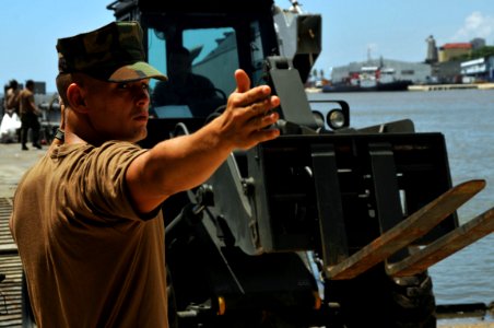 US Navy 081003-N-8907D-653 Equipment Operator Constructionman Stephen Colprit directs vehicles off a landing craft unit photo