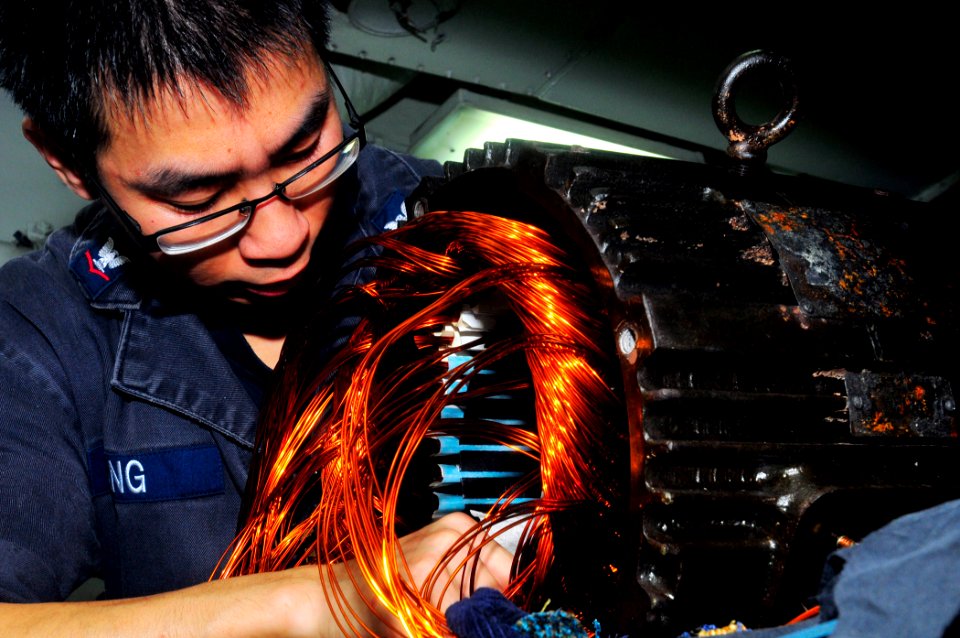 US Navy 101004-N-4378P-037 Electrician's Mate 3rd Class Mike Yang recoils a ventilation motor aboard the amphibious assault ship USS Peleliu (LHA 5