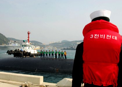 US Navy 081004-N-9573A-002 A Republic of Korea Sailor watches Sailors aboard the USS Buffalo (SSB 715) as the submarine pulls into the port of Pusan