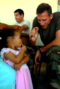 US Navy 081007-N-3595W-078 Lt. Cmdr. Nathan Uebelhoer, a dermatologist embarked aboard the amphibious assault ship USS Kearsarge (LHD 3), talks with a little girl at a local medical clinic during a community service project in photo