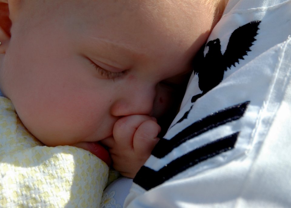 US Navy 081005-N-1522S-023 A baby falls asleep in her father's arms during the homecoming for the guided-missile frigate USS McInerney (FFG 8) to at Naval Station Mayport after a six-month deployment