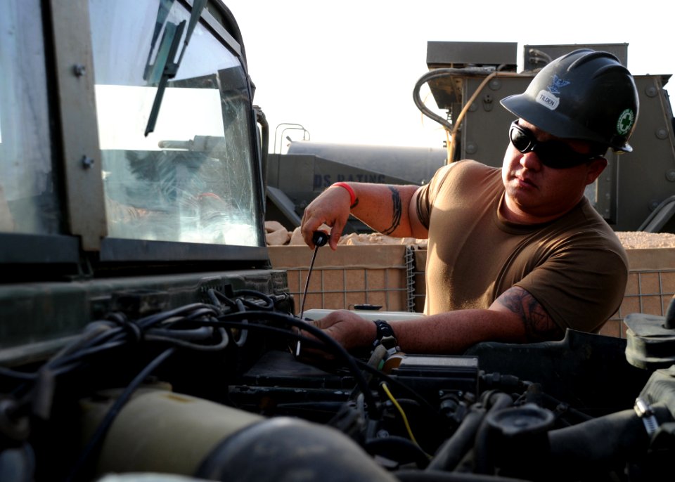 US Navy 081006-N-1120L-024 Equipment Operator 3rd Class Jason Tilden checks the oil levels in a high mobility multipurposed wheeled vehicle