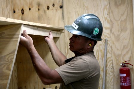 US Navy 081006-N-9623R-072 Builder 2nd Class Jorge Gaitan installs shelving units for a medical facility photo