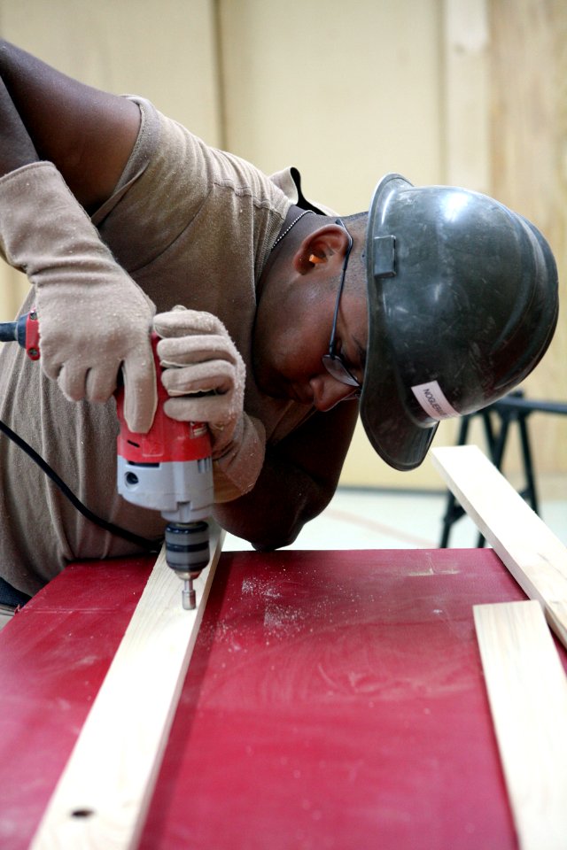 US Navy 081006-N-9623R-073 Builder Constructionman Saulo Nogueravega drills holes in shelving support braces