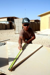 US Navy 081006-N-9623R-176 Builder 2nd Class Jorge Gaitan measures section of lumber that will be used to construct shelving units photo