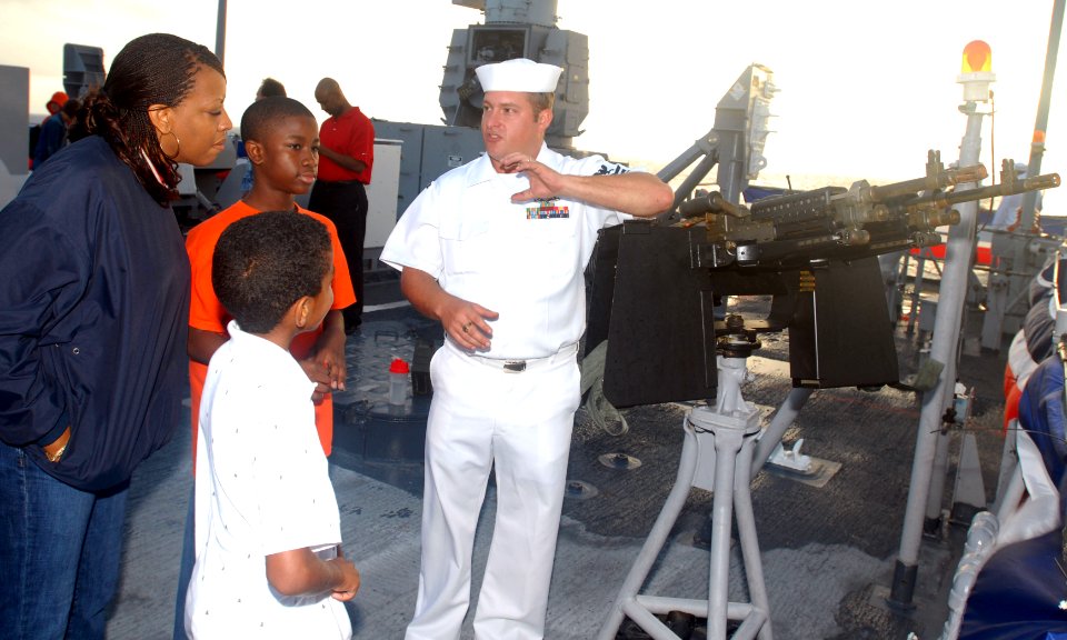 US Navy 081010-N-0486G-001 Gunner's Mate 1st Class Jerry Hawk shows his gun mount and sea and anchor position to guests