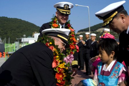 US Navy 081008-N-9123L-003 Lt. Cmdr. Robert Ogden, executive officer of the guided-missile destroyer USS John S. McCain (DDG 56), thanks a Korean child after receiving a traditional flower wreath presented to welcome McCain to