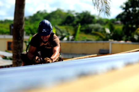 US Navy 081009-N-4515N-144 Air Force Tech Sgt. Scott Boucher works on the roof of a school house photo