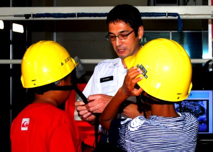 US Navy 081007-N-0483B-003 Hiroaki Kawai, a member of Yokosuka's Commander Naval Forces Japan (CNFJ) Regional Fire Department, assists students from The Sullivans Elementary School as they don safety helmets photo