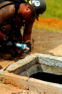 US Navy 081009-N-4515N-312 Equipment Operator 2nd Class Carlos Guzman cuts rebar to create a well covering at a local school