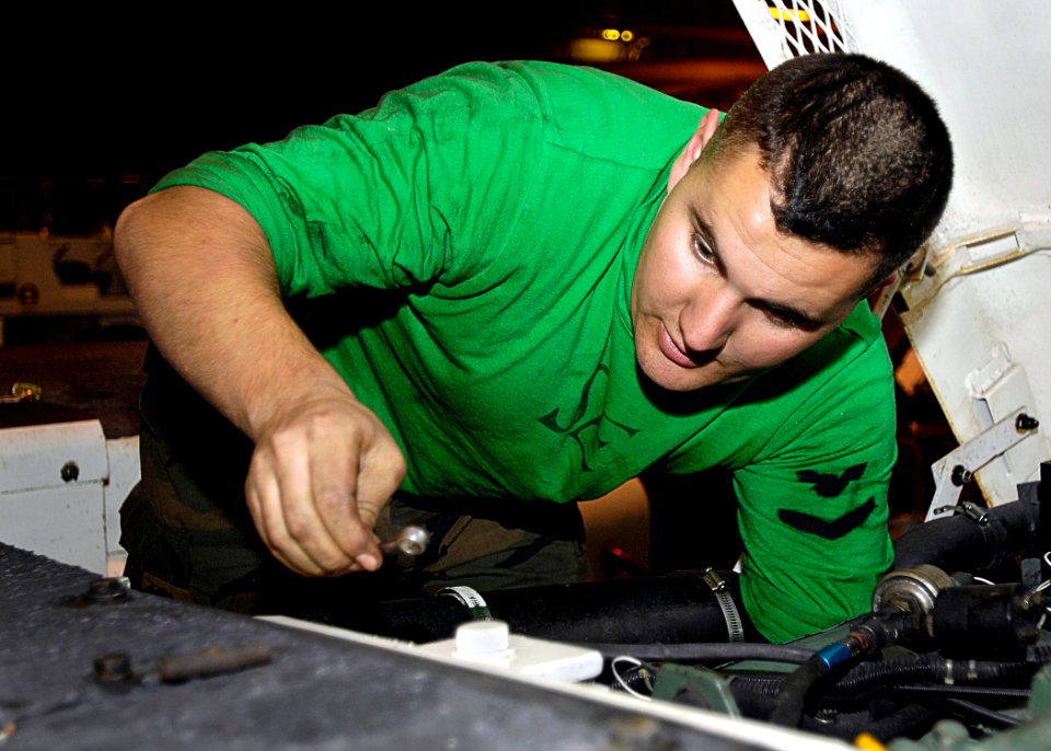 US Navy 081011-N-4954I-001 Aviation Support Equipment Technician 3rd Class Ben Rapp uses a wrench to adjust the engine throttle on a tow tractor
