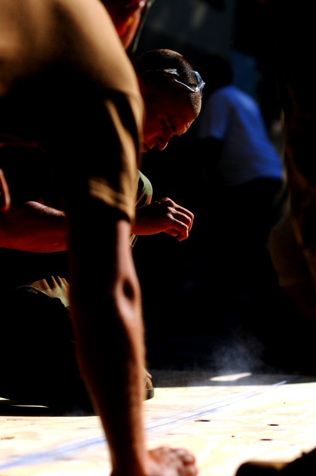 US Navy 081010-N-4515N-011 Air Force Airman 1st Class Ryan Moran snaps a chalk line on a sheet of plywood