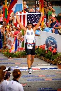 US Navy 081011-N-6674H-003 Lt. Cmdr. Damon Dixon waves the American flag as he crosses the finish line at the 30th Ford Ironman World Championship