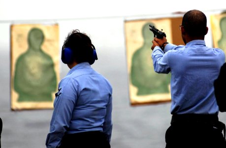 US Navy 081009-N-9928E-102 Aviation Electronics Technician 3rd Class Joshua Robbins, from Creekville S.C, right, fires a 9mm pistol as Aviation Ordnanceman 3rd Class Elizabeth Vandenberg, from Los Angeles, observes during small