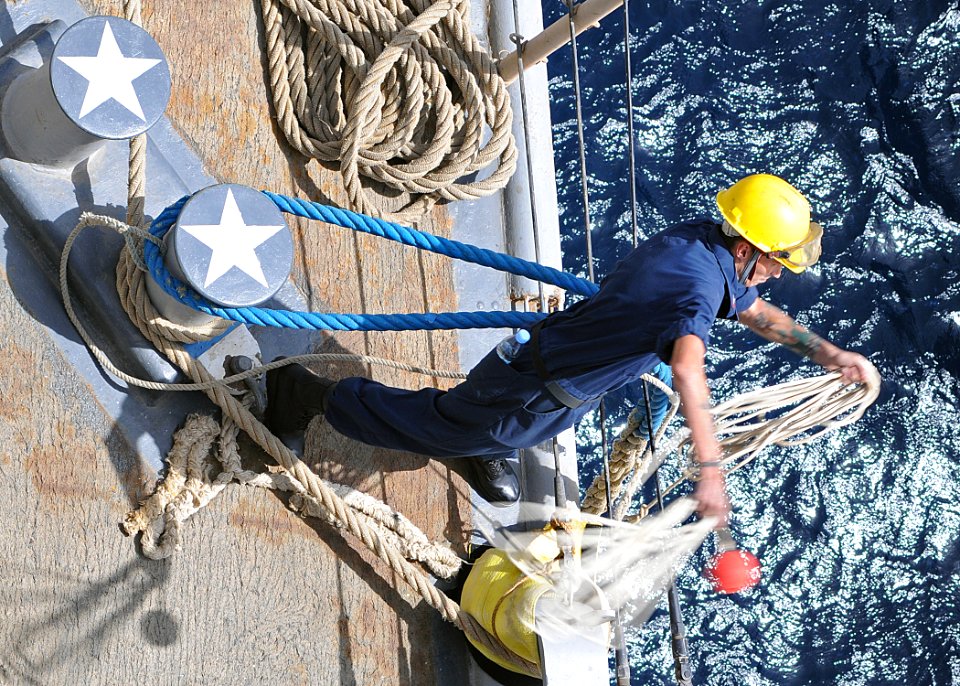 US Navy 100621-N-1082Z-031 Boatswains Mate 2nd Class Joshua J. Johnfroe, from West Wego, La., throws the lead of a mooring line to the pier