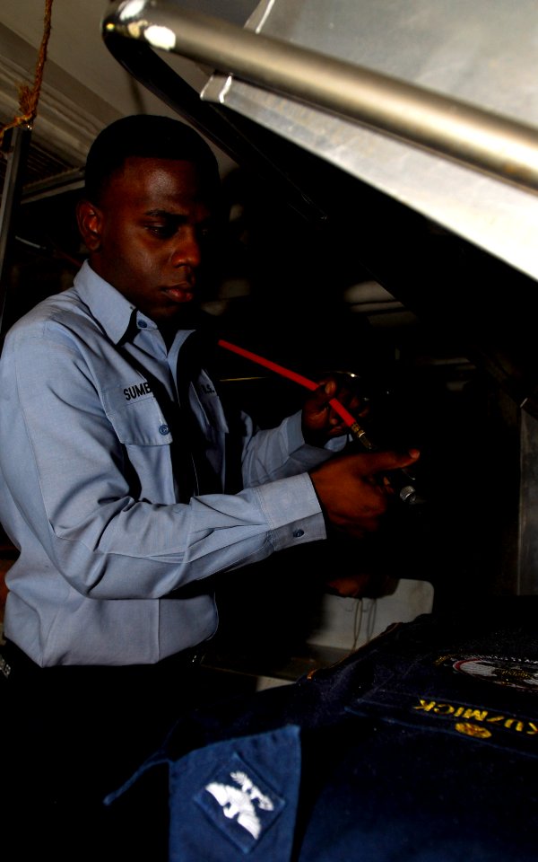 US Navy 081011-N-9610C-049 Aviation Boatswain's Mate (Handling) Airman Patrick Sumbler steam-presses coveralls
