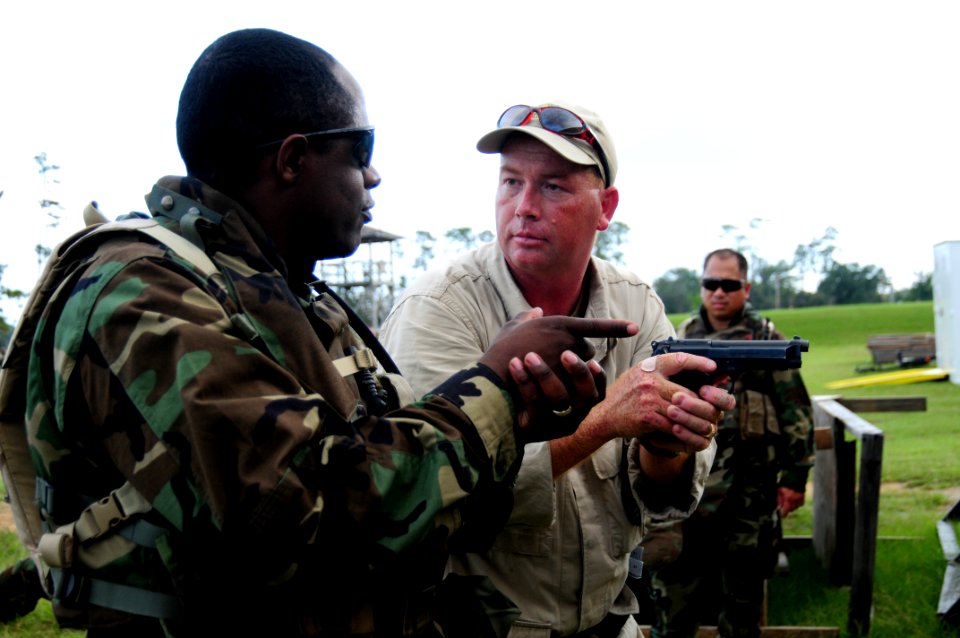 US Navy 081014-N-0411D-036 Former Seabee Chief Richard Rader, right, describes to Boatswain's Mate 1st Class Kenneth Scales how properly gripping a handgun can affect marksmanship during tactical handgun marksmanship training