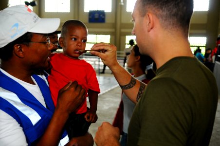 US Navy 081015-N-4515N-198 Canadian Army Pvt. David Pivato, embarked aboard the amphibious assault ship USS Kearsarge (LHD 3), administers an anti-parasitic medication to a young Dominican boy photo