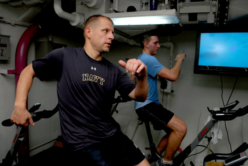 US Navy 081012-N-4005H-238 Senior Chief Aviation Boatswain's Mate (Handling) Trenton Schmidt participates in a spin class in the forward gym aboard the Nimitz-class aircraft carrier USS Ronald Reagan (CVN 76)
