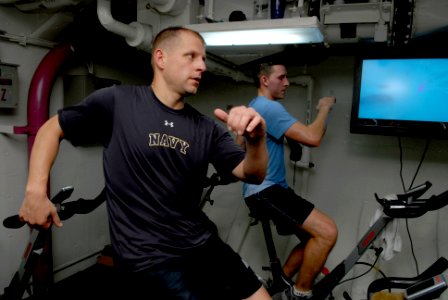 US Navy 081012-N-4005H-238 Senior Chief Aviation Boatswain's Mate (Handling) Trenton Schmidt participates in a spin class in the forward gym aboard the Nimitz-class aircraft carrier USS Ronald Reagan (CVN 76)