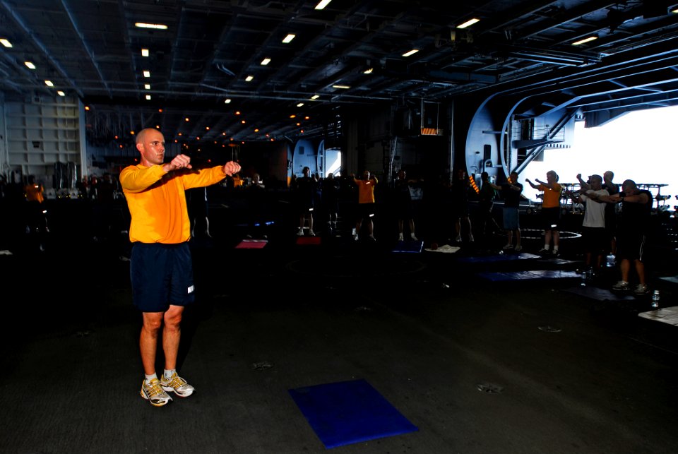 US Navy 081013-N-9610C-050 Chief Fire Controlman Robert Church of Monterey, Calif., leads a group physical training session in the hangar bay aboard the Nimitz-class aircraft carrier USS John C. Stennis (CVN 74)