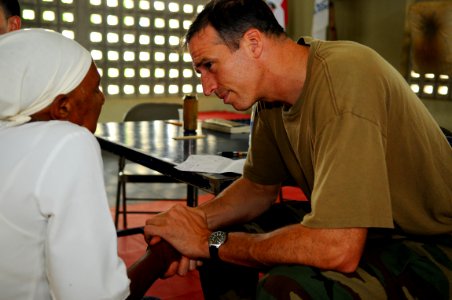 US Navy 081015-N-4515N-268 Lt. Cmdr. Nathan Uebelhoer, a medical augmentee embarked aboard the amphibious assault ship USS Kearsarge (LHD 3), speaks with a Dominican woman about her ailments photo
