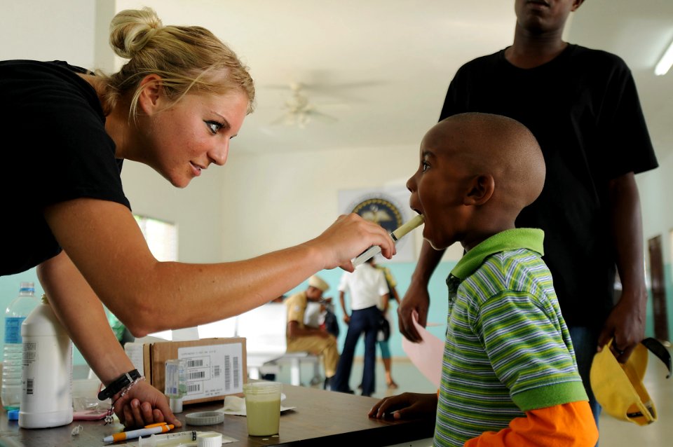 US Navy 081016-N-5642P-065 Airman 1st Class Alexandra Olson, embarked aboard the amphibious assault ship USS Kearsarge (LHD 3), gives a Dominican boy a dose of de-worming formula at the 27 Febrero