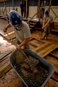 US Navy 081013-N-9620B-002 Tech Sgt. Derron Price, embarked aboard embarked aboard the amphibious assault ship USS Kearsarge (LHD 3), shovels gravel into the foundation of a boardwalk photo