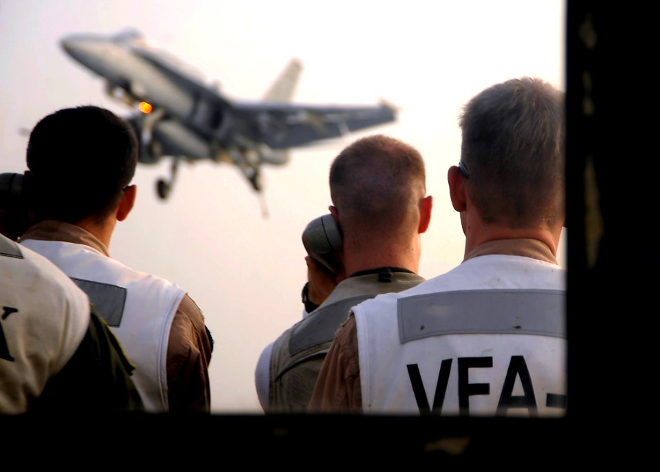 US Navy 081016-N-7571S-011 Landing signal officers communicate with the pilot of an F-A-18 Hornet as he approaches the flight deck for an arrested landing aboard the aircraft carrier USS Theodore Roosevelt (CVN 71)