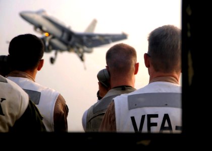 US Navy 081016-N-7571S-011 Landing signal officers communicate with the pilot of an F-A-18 Hornet as he approaches the flight deck for an arrested landing aboard the aircraft carrier USS Theodore Roosevelt (CVN 71)