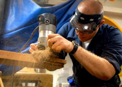 US Navy 081013-N-9900B-003 Hull Maintenance Technician Fireman Matt Brandsma assigned to the aircraft carrier USS Theodore Roosevelt's (CVN 71) repair division operates a router on a carrier plaque
