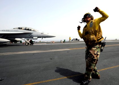 US Navy 081016-N-7241L-034 Aviation Boatswain's Mate 3rd Class Stephen Vaiza communicates with the pilots of an F-A-18F Super Hornet strike fighter assigned to the