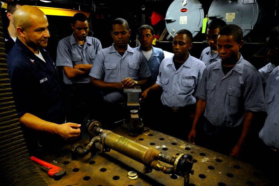 US Navy 081014-N-4515N-020 Damage Controlman 2nd Class Francisco Rincon translates instructions to Dominican Republic sailors on how to weld during a subject matter expert exchange aboard the amphibious assault ship USS Kearsar