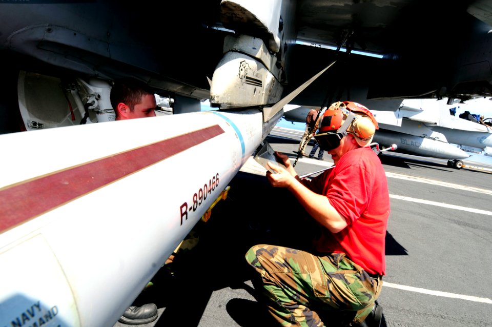 US Navy 081014-N-7918H-107 Aviation Ordnanceman 2nd Class Paul Schmitt and Aviation Ordnanceman 3rd Class Cody Dalrymple attach missiles to an aircraft