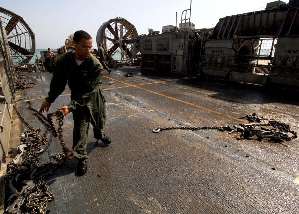 US Navy 081018-N-4236E-276 Yeoman Seaman Brian Colbert moves chains across the deck of a landing craft air cushion assigned to Assault Craft Unit (ACU) 4 from the multi-purpose amphibious assault ship USS Iwo Jima (LHD 7)