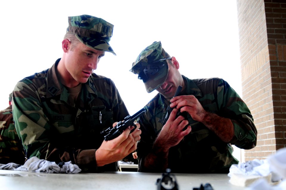 US Navy 081017-N-0411D-020 Lt. Timm Heisey, left, and Electronics Technician 1st Class Justin Donette clean their Beretta 9mm pistols at the armory's cleaning station. Heisey and Donnette are training in handgun marksmanship